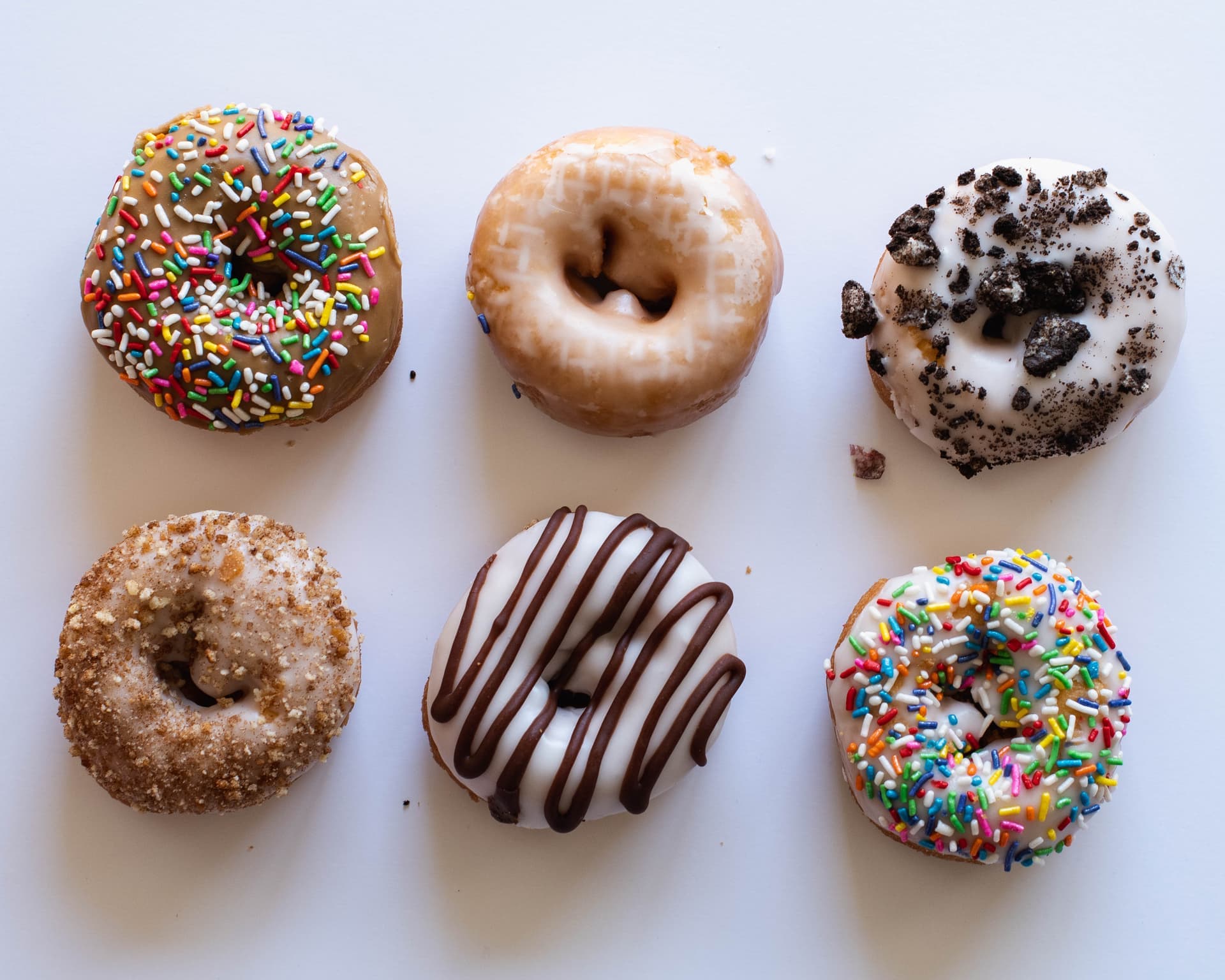 Assorted vegan donuts with sprinkles, glaze, chocolate drizzle, and cookies and cream toppings