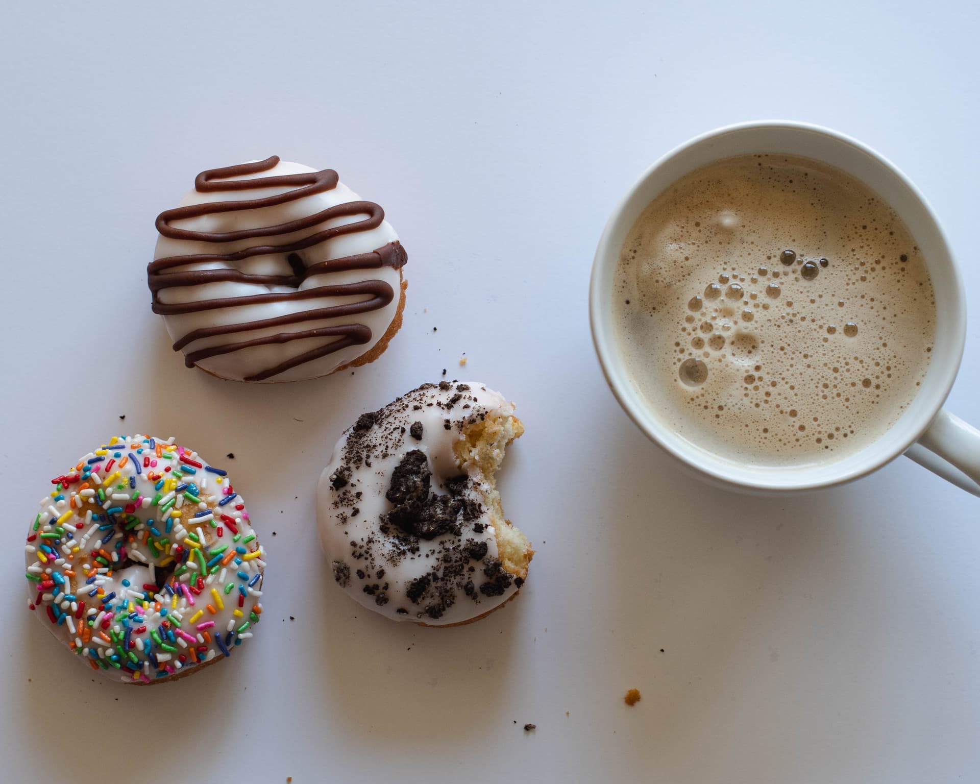 Three vegan donuts paired with coffee cup flatlay