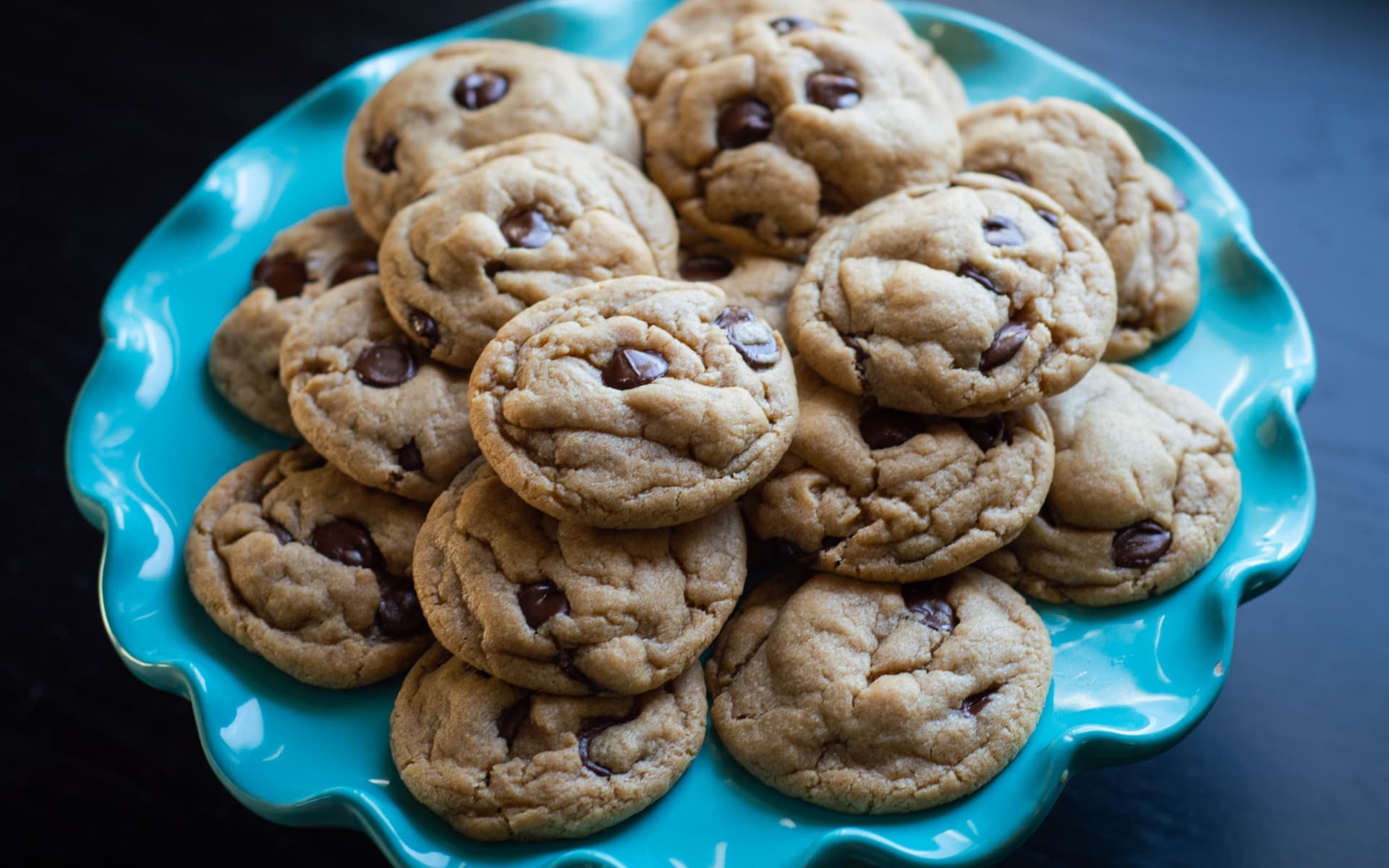 Chocolate chip cookies piled on turquoise scalloped plate