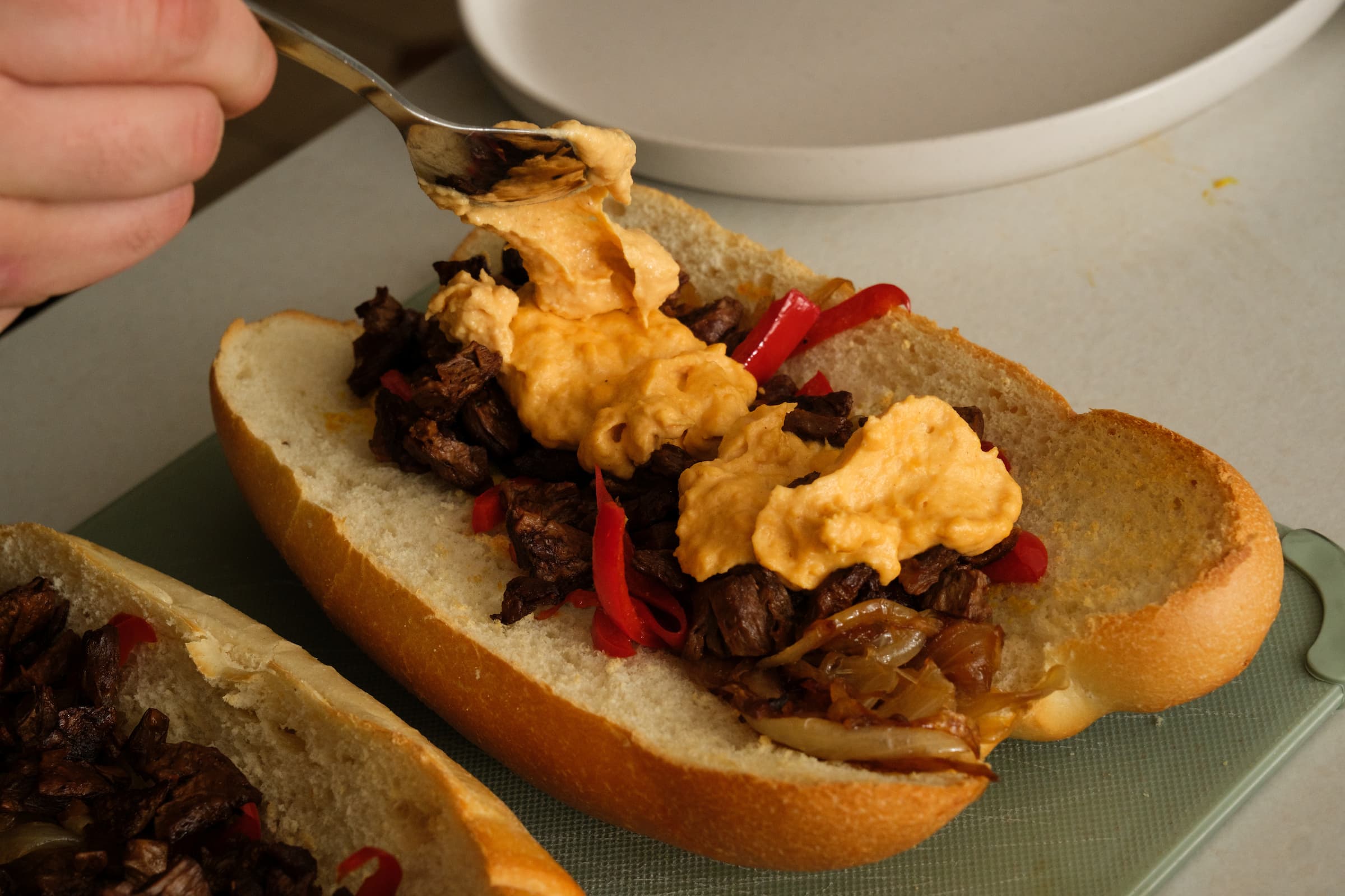 Spooning cheese whiz onto the sandwich